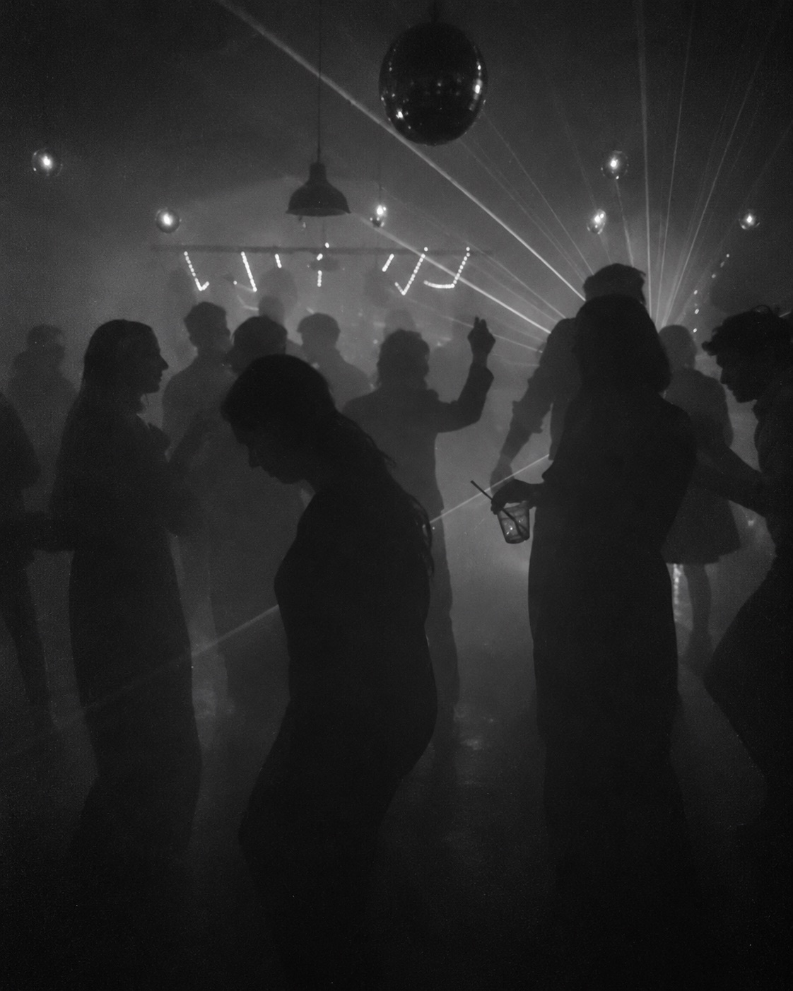 Tanzende Gäste als Silhouetten im Nebel, Discokugel und Lichtstrahlen
